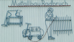 Bild: Metallarbeit am Giebel der Werkstatthalle, zeigt einen Schweisser bei der Arbeit